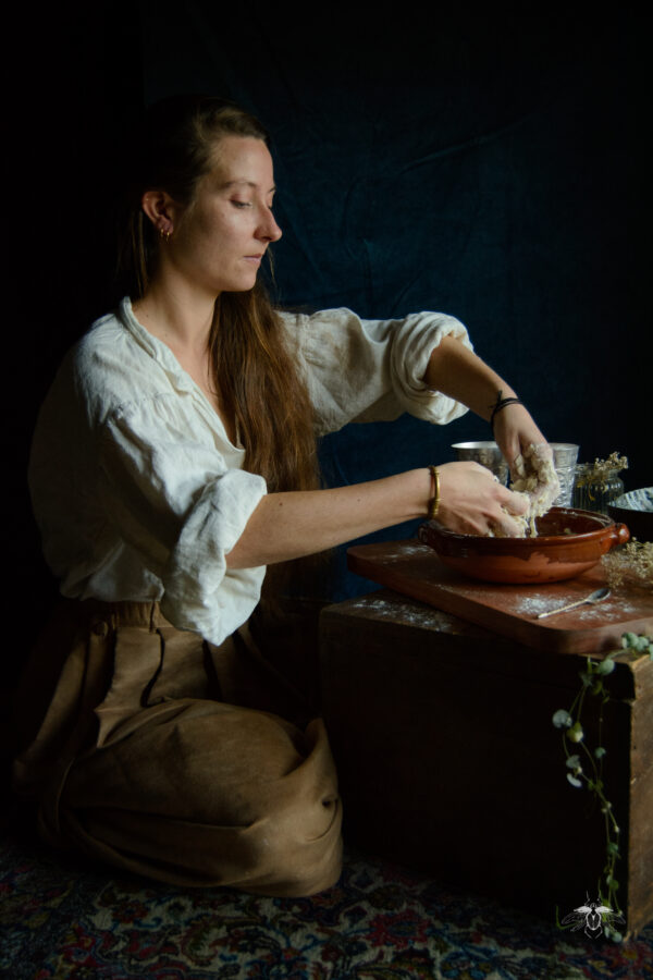 Séance d'inspiration tableau fine art de la laitière de Vermeer réalisée avec Mademoiselle Danielou. On y voit mademoiselle Danielou en train de mélanger une préparation avec les mains dans un plat.